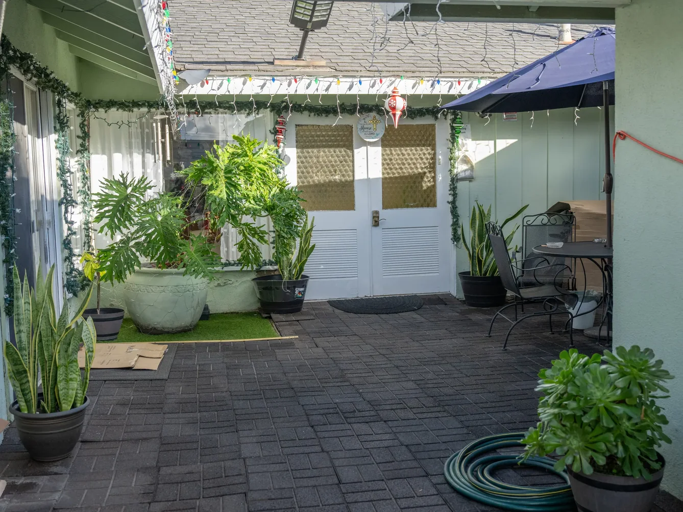 Covered outdoor patio area with comfortable seating and greenery.