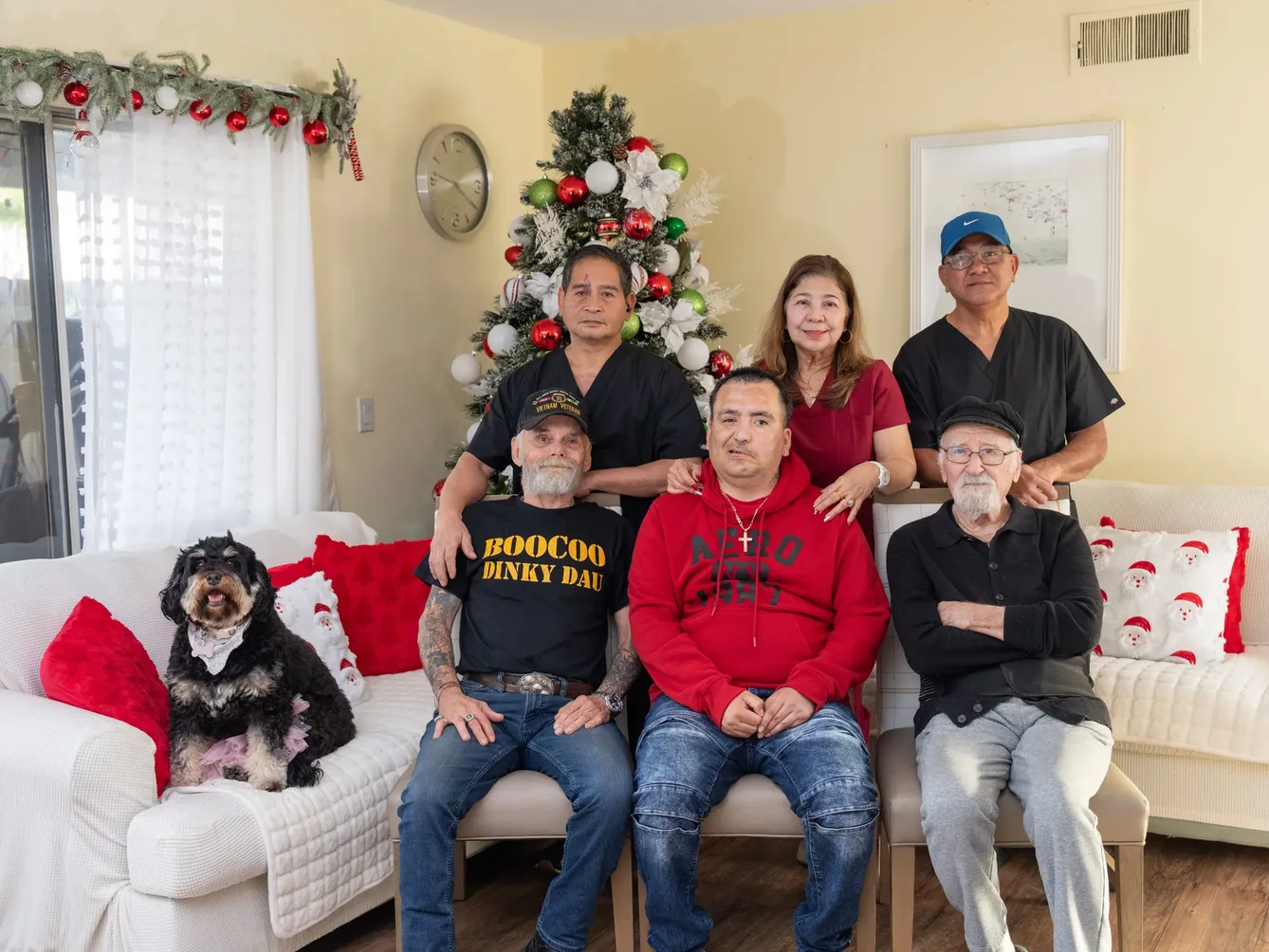 Family group with caregivers gathered in festively decorated living room.